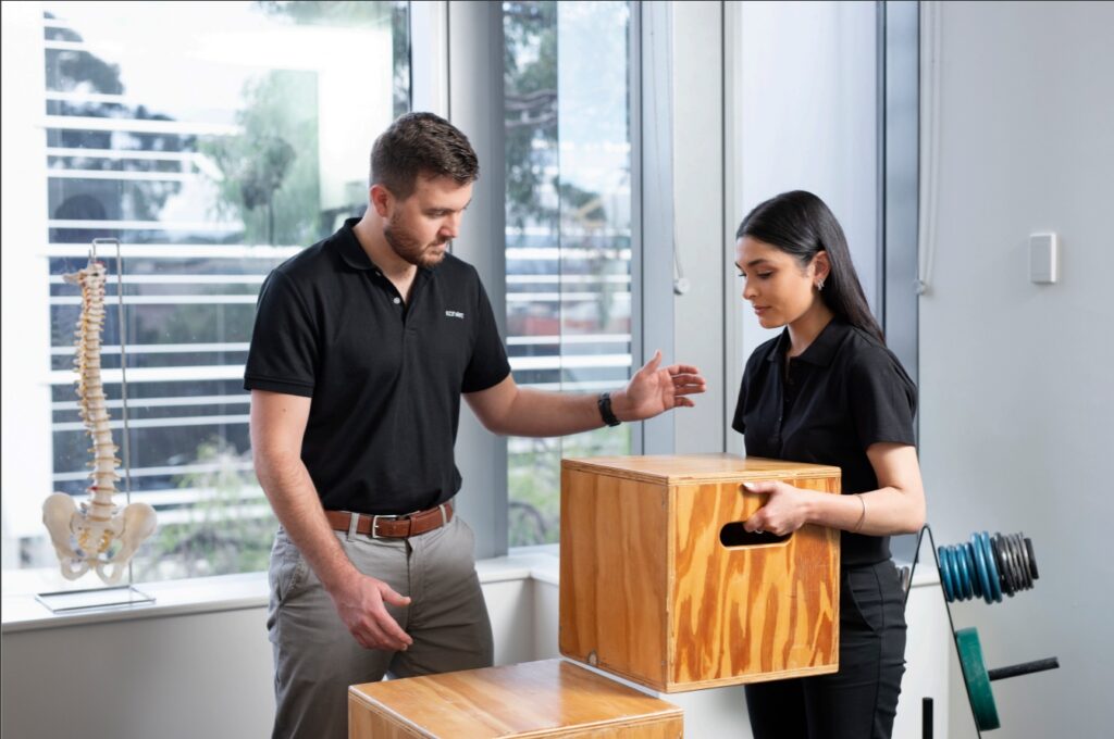 Physiotherapist showing patient how to correctly lift a box